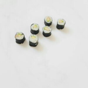 Minimalistic presentation of sushi rolls on a white marble background.